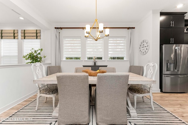 dining area with light wood-type flooring, a chandelier, and crown molding