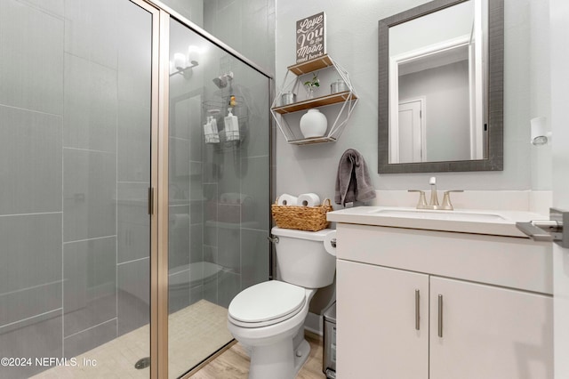 bathroom featuring hardwood / wood-style floors, walk in shower, vanity, and toilet