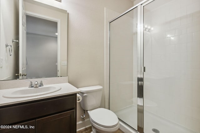 bathroom featuring vanity, toilet, and a shower with door