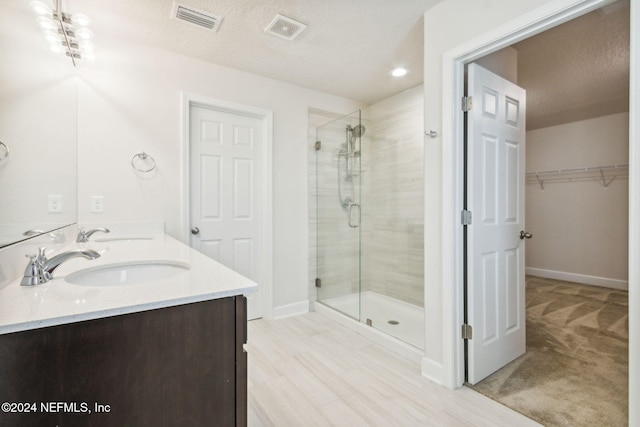 bathroom with vanity, wood-type flooring, a shower with door, and a textured ceiling