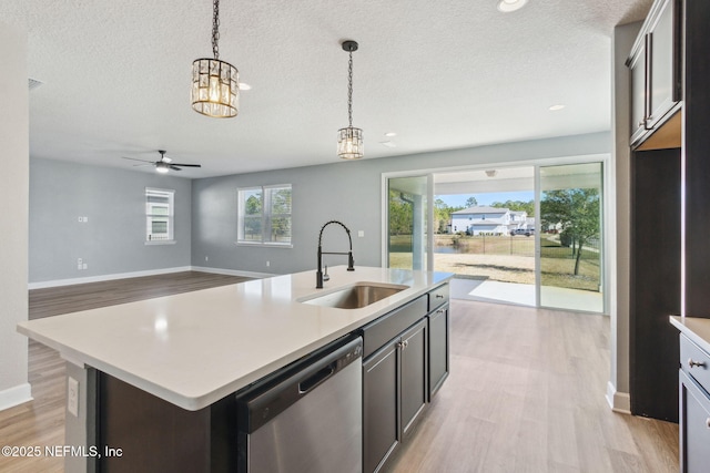 kitchen with ceiling fan with notable chandelier, sink, decorative light fixtures, dishwasher, and an island with sink