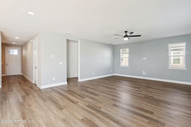 empty room with a textured ceiling, light wood-type flooring, and ceiling fan