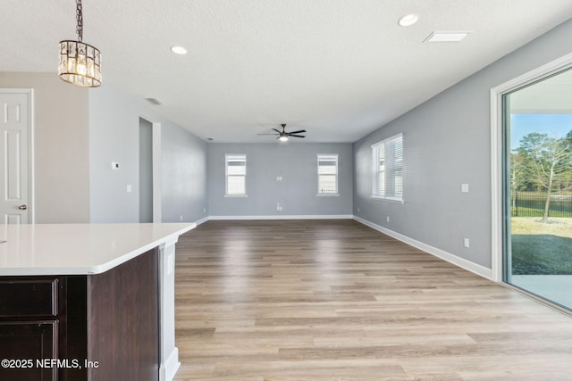 unfurnished living room with light wood-type flooring, a textured ceiling, and ceiling fan with notable chandelier