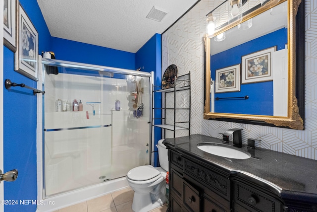 bathroom featuring a textured ceiling, walk in shower, toilet, vanity, and tile patterned floors