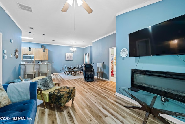 living room with crown molding, light hardwood / wood-style flooring, and ceiling fan with notable chandelier