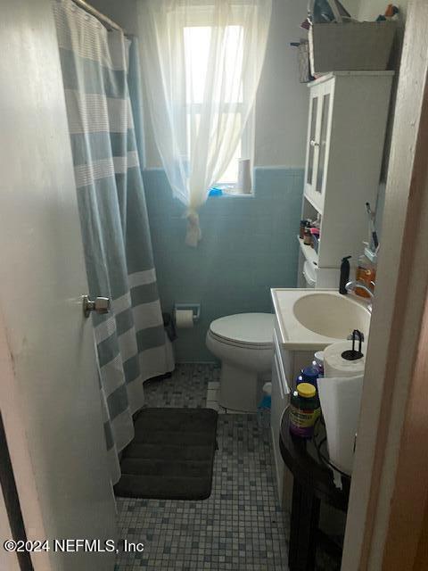 bathroom featuring tile patterned floors, toilet, vanity, a shower with shower curtain, and tile walls