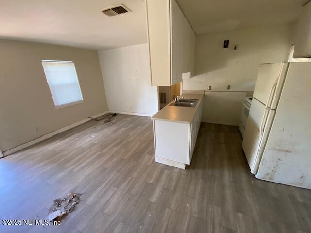 kitchen featuring visible vents, freestanding refrigerator, wood finished floors, white cabinets, and a sink