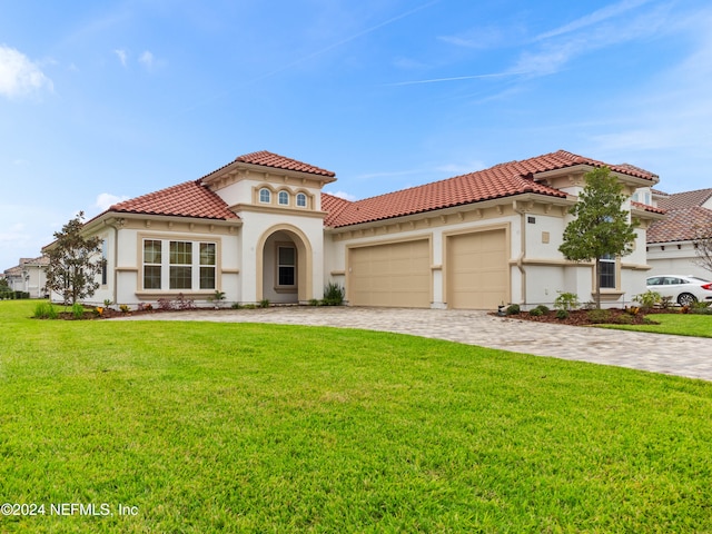 mediterranean / spanish home featuring a front yard and a garage