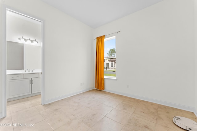 unfurnished bedroom featuring light tile patterned flooring, sink, and ensuite bath