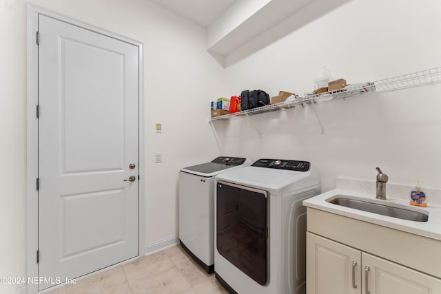 laundry area with cabinets, light tile patterned floors, washer and clothes dryer, and sink