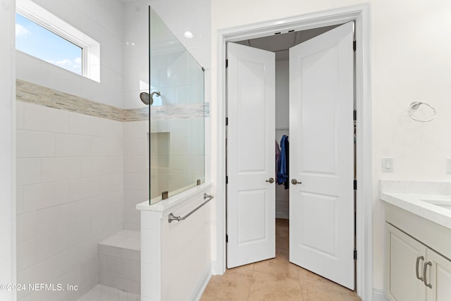 bathroom with tile patterned floors, vanity, and a tile shower