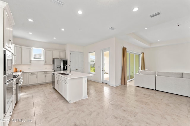 kitchen with white cabinetry, a kitchen island with sink, sink, and appliances with stainless steel finishes