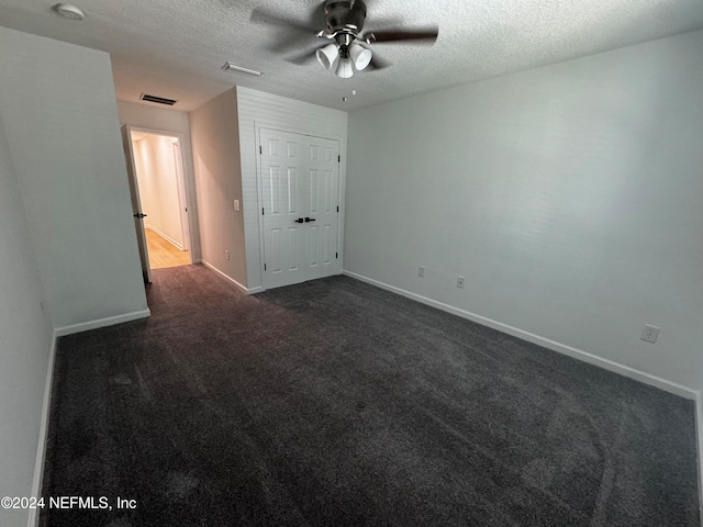 unfurnished bedroom featuring a textured ceiling, dark colored carpet, and ceiling fan