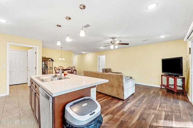 kitchen featuring ceiling fan, pendant lighting, stainless steel dishwasher, light hardwood / wood-style flooring, and a kitchen island with sink