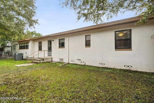 back of house featuring central air condition unit and a yard