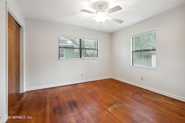 unfurnished bedroom featuring a closet, multiple windows, wood-type flooring, and ceiling fan