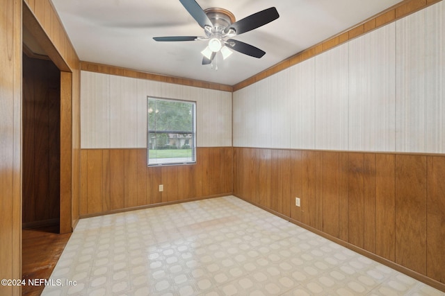 spare room featuring wood walls and ceiling fan