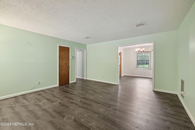 unfurnished room featuring dark hardwood / wood-style flooring, an inviting chandelier, and a textured ceiling