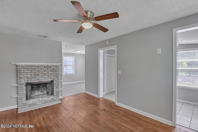 2112 Prospect St, Jacksonville, FL 32254 - unfurnished living room with wood finished floors, a textured ceiling, visible vents, a fireplace, and a ceiling fan