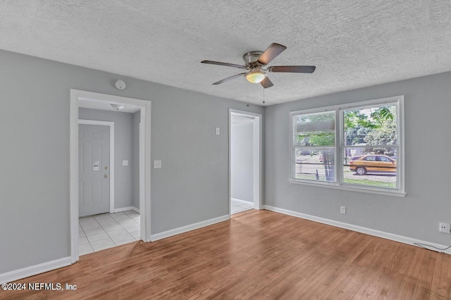 unfurnished room featuring light wood-type flooring, a textured ceiling, and ceiling fan