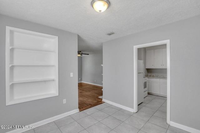 hall with light hardwood / wood-style floors, built in features, and a textured ceiling