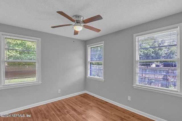 unfurnished room with hardwood / wood-style flooring, plenty of natural light, and a textured ceiling