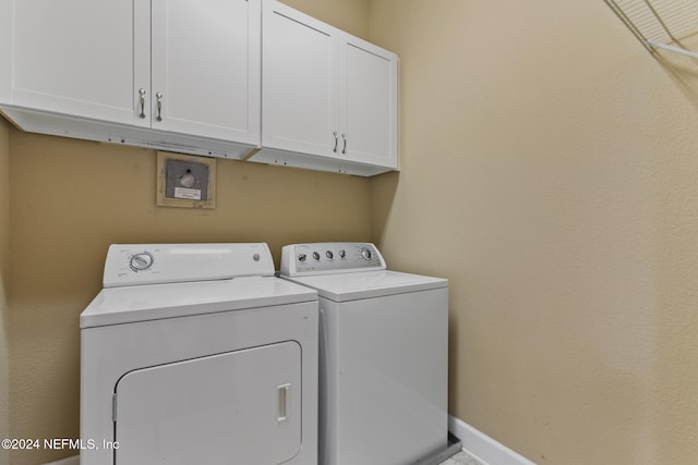 clothes washing area with washer and clothes dryer and cabinets