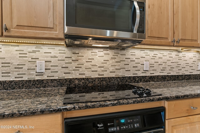 kitchen with dark stone countertops, black appliances, and tasteful backsplash