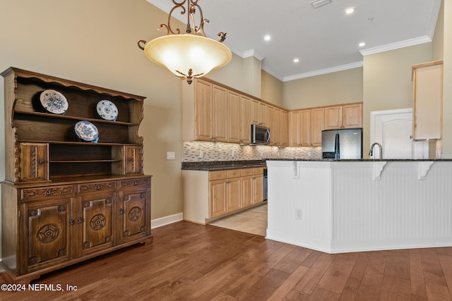 kitchen with kitchen peninsula, appliances with stainless steel finishes, a breakfast bar area, light wood-type flooring, and pendant lighting