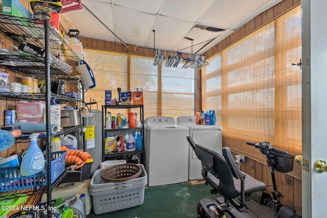 interior space featuring electric water heater, carpet floors, washer and clothes dryer, and wooden walls