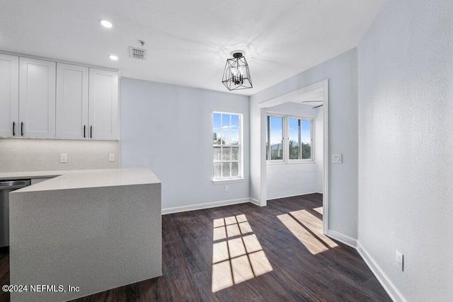 kitchen with white cabinets, hanging light fixtures, dark hardwood / wood-style floors, and an inviting chandelier