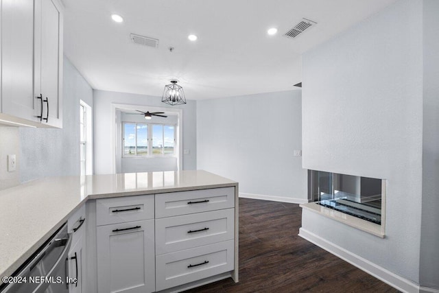 kitchen featuring kitchen peninsula, dark hardwood / wood-style flooring, ceiling fan with notable chandelier, dishwasher, and white cabinetry