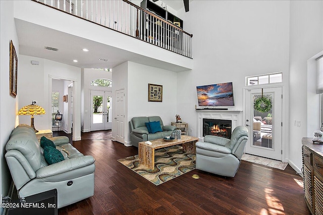 living room featuring a high ceiling, a wealth of natural light, and dark hardwood / wood-style floors