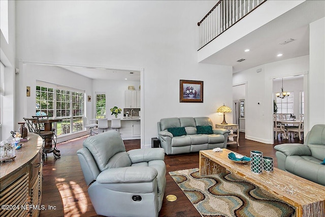 living room featuring a towering ceiling, dark hardwood / wood-style floors, and a chandelier