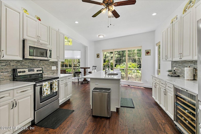 kitchen featuring a wealth of natural light, white cabinetry, beverage cooler, and appliances with stainless steel finishes