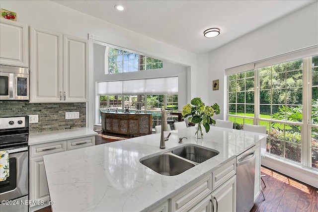 kitchen featuring white cabinets, light stone countertops, sink, and appliances with stainless steel finishes