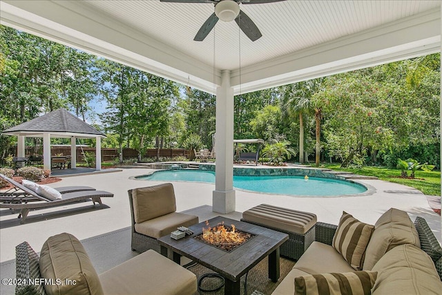 view of swimming pool featuring ceiling fan, an outdoor living space with a fire pit, a gazebo, and a patio area