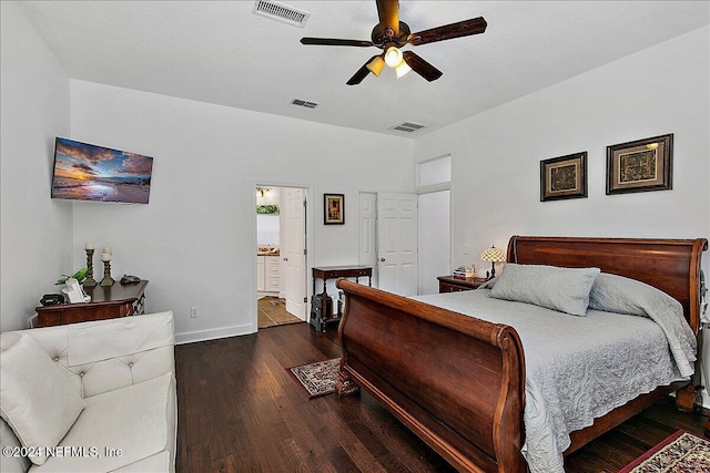 bedroom with a textured ceiling, dark hardwood / wood-style flooring, ceiling fan, and connected bathroom