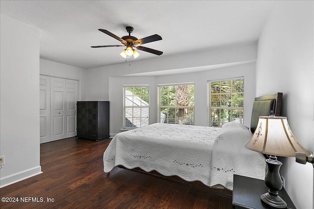 bedroom with dark wood-type flooring, ceiling fan, multiple windows, and a closet