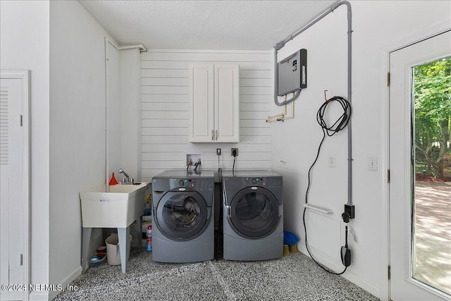 clothes washing area featuring cabinets, wood walls, a textured ceiling, and independent washer and dryer