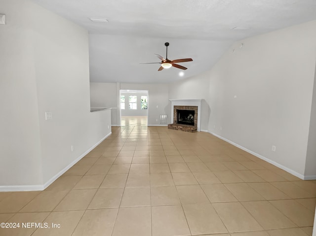 unfurnished living room featuring a brick fireplace, light tile patterned flooring, ceiling fan, and lofted ceiling