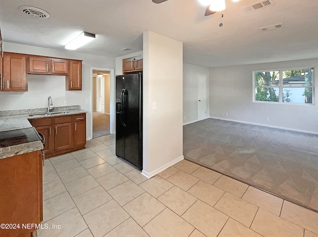 kitchen with light tile patterned floors, ceiling fan, black fridge, and sink