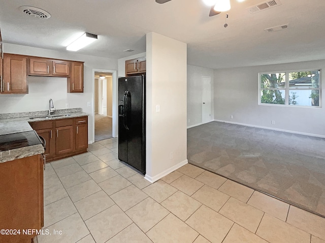 5225 Royce Ave, Jacksonville, FL 32205 - kitchen with black fridge with ice dispenser, light carpet, a sink, light tile patterned floors, and brown cabinets