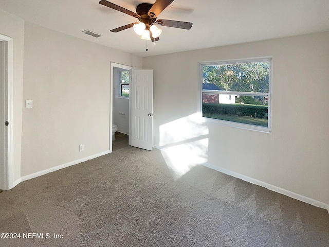 unfurnished room with dark colored carpet and ceiling fan