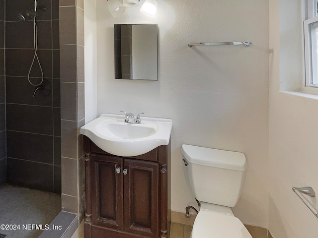 bathroom featuring vanity, toilet, and tiled shower