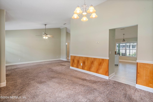 carpeted spare room with ceiling fan with notable chandelier, wooden walls, and high vaulted ceiling