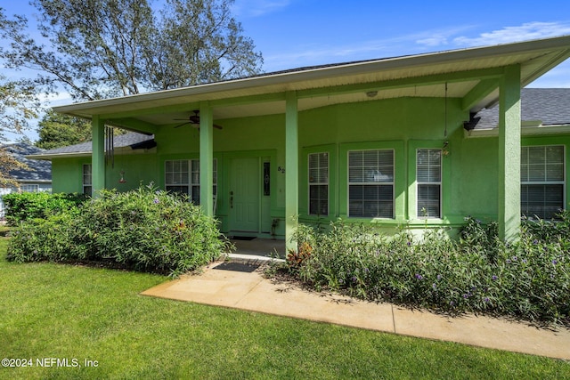 doorway to property with a lawn and ceiling fan