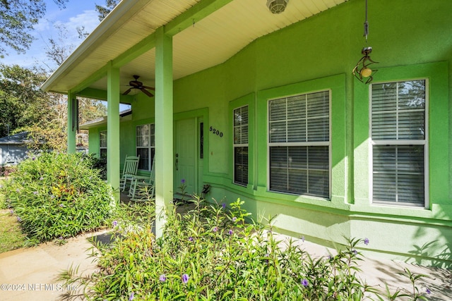 view of exterior entry with ceiling fan and a porch