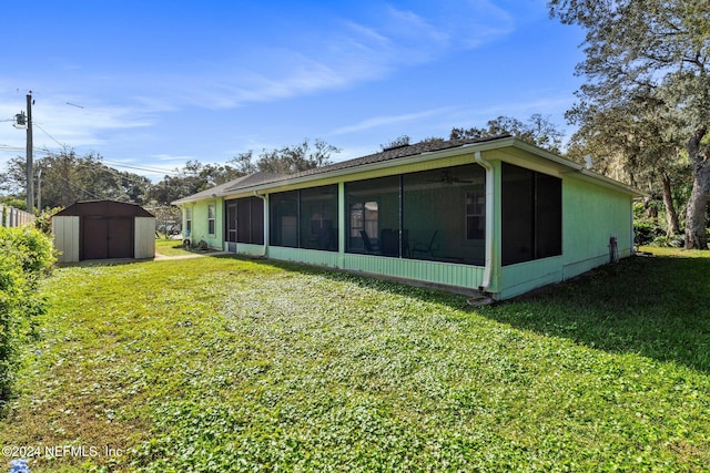 rear view of house with a sunroom, a yard, and a storage shed