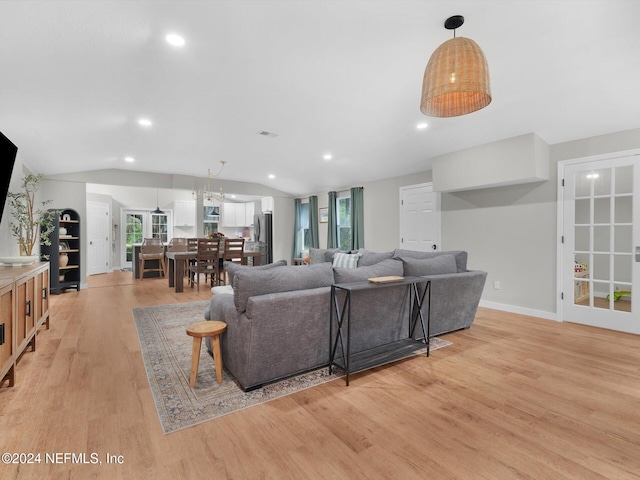 living room with light hardwood / wood-style floors, a healthy amount of sunlight, and lofted ceiling